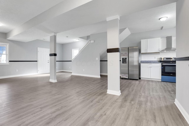 kitchen with wall chimney exhaust hood, tasteful backsplash, appliances with stainless steel finishes, light hardwood / wood-style floors, and white cabinets