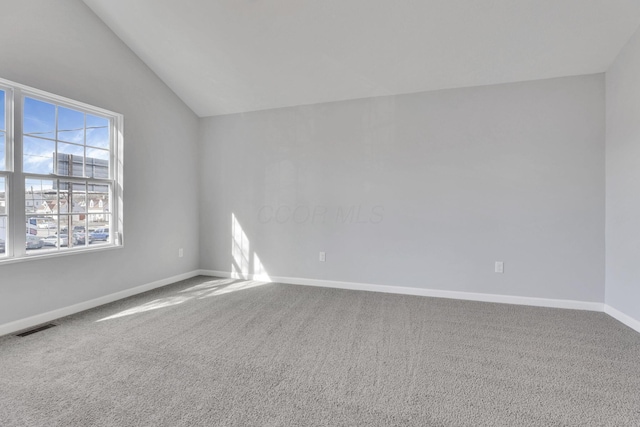 carpeted spare room featuring lofted ceiling and plenty of natural light