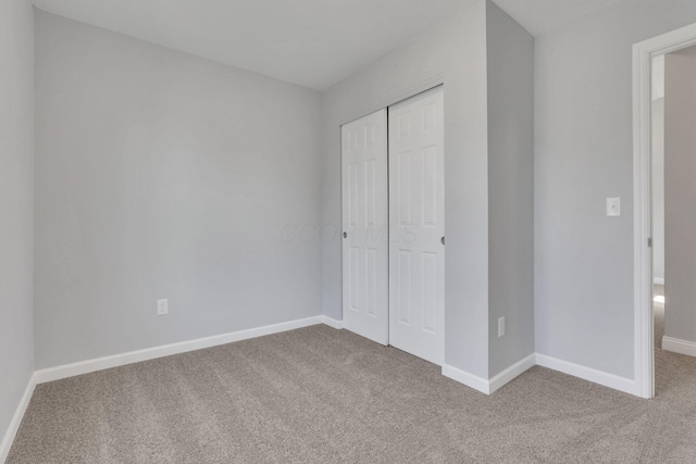 unfurnished bedroom featuring light colored carpet and a closet