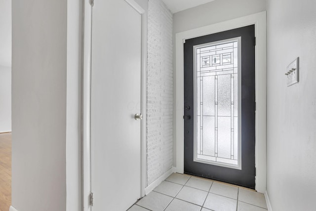 foyer with light tile patterned floors and brick wall