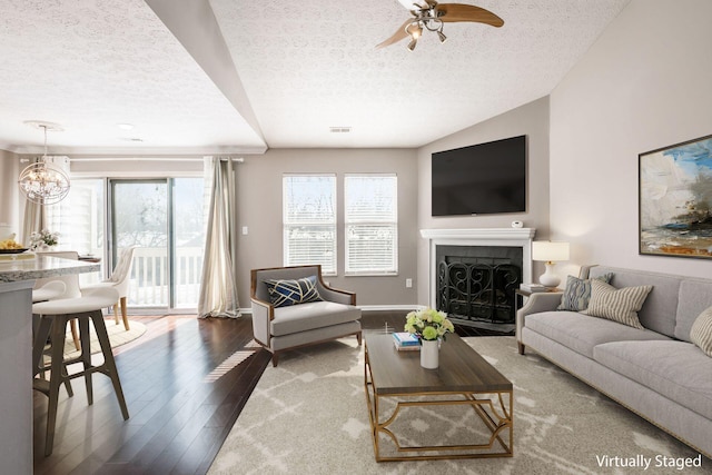 living room featuring a textured ceiling, a fireplace, wood finished floors, and a healthy amount of sunlight