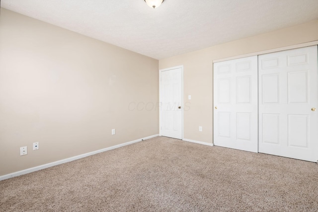 unfurnished bedroom with a textured ceiling, a closet, carpet flooring, and baseboards