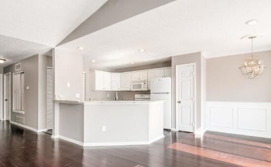 kitchen with decorative light fixtures, light countertops, white cabinetry, white appliances, and a peninsula