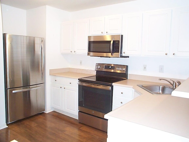 kitchen with stainless steel appliances, dark wood-type flooring, a sink, white cabinetry, and light countertops