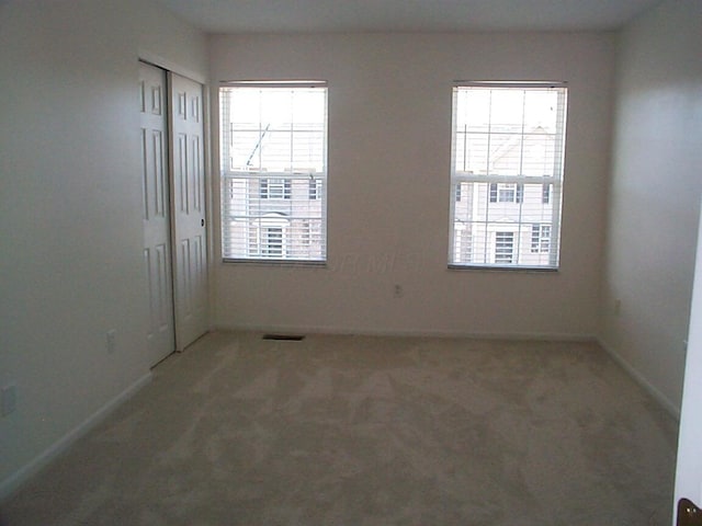 unfurnished room with carpet, visible vents, and baseboards