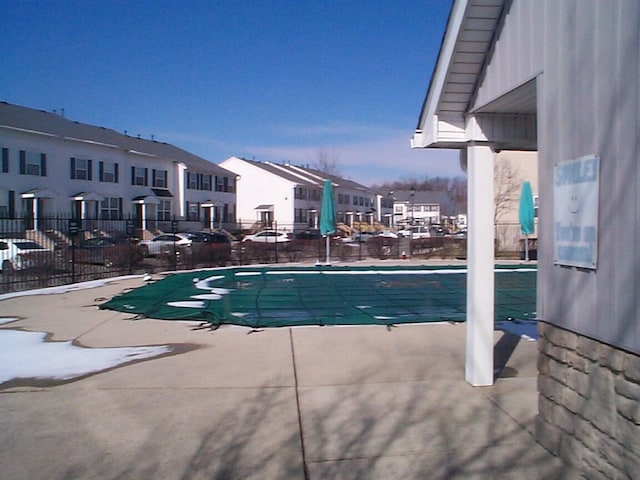 community pool with a patio area, fence, and a residential view