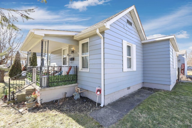 view of home's exterior with covered porch and a lawn