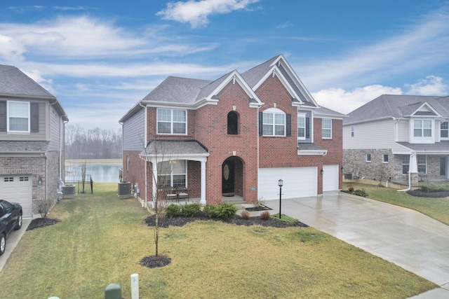 view of front of house with a garage, a front yard, central air condition unit, and a water view