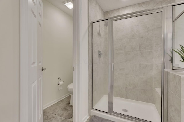 bathroom featuring toilet and a shower with shower door