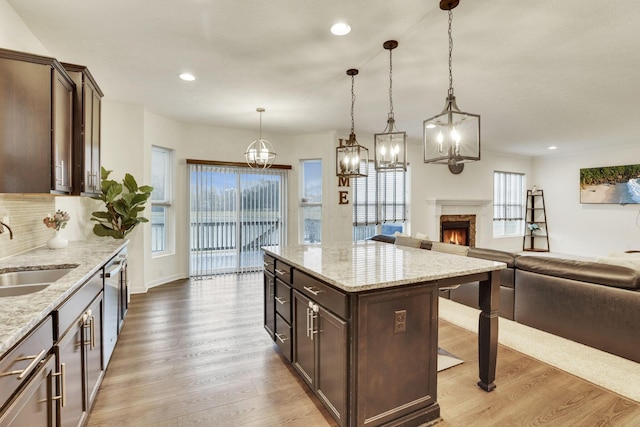 kitchen with a kitchen island, sink, dark brown cabinetry, and decorative light fixtures