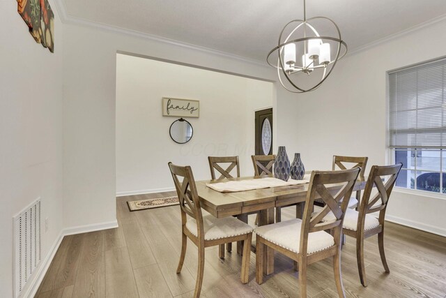 dining room featuring ornamental molding, a notable chandelier, and light hardwood / wood-style flooring