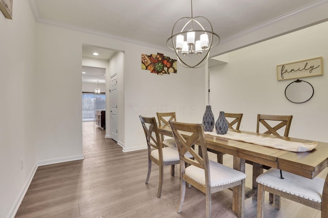 dining area with crown molding, wood-type flooring, and a notable chandelier