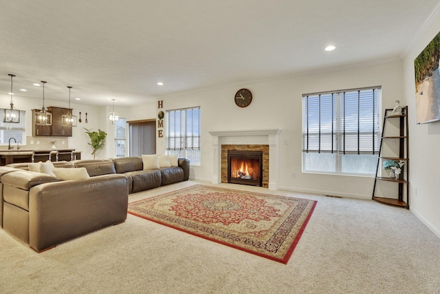 carpeted living room featuring ornamental molding, plenty of natural light, a chandelier, and sink