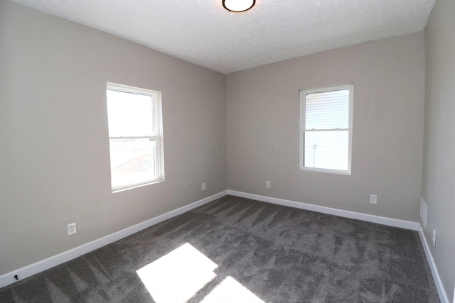 empty room featuring dark colored carpet and a textured ceiling