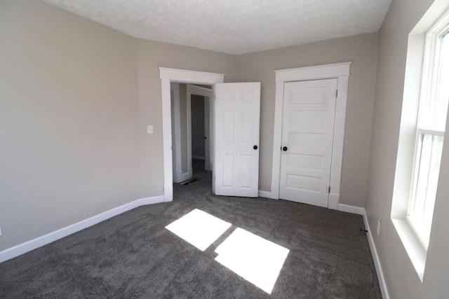 unfurnished bedroom featuring a textured ceiling and dark colored carpet