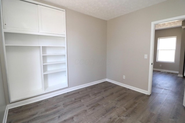 unfurnished bedroom with dark hardwood / wood-style flooring, a textured ceiling, and a closet