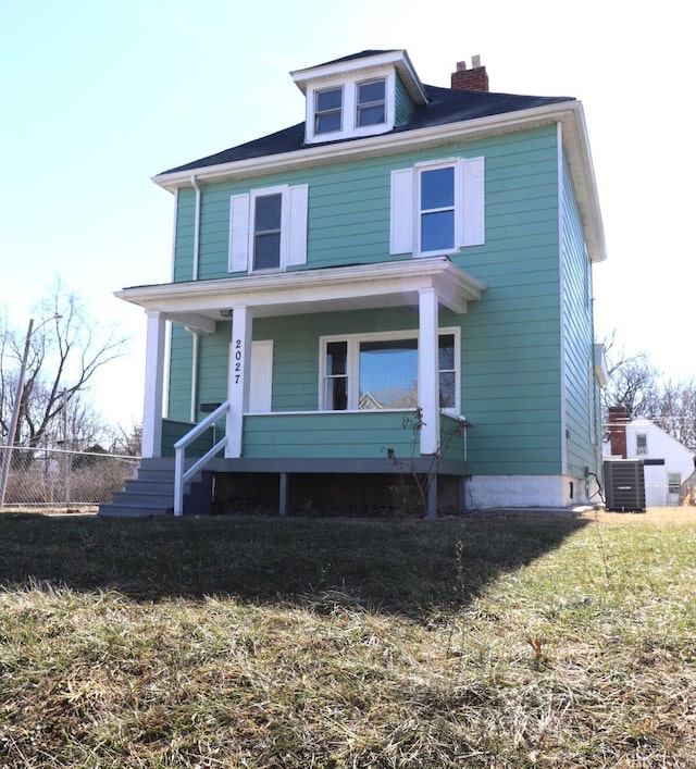 view of front facade featuring cooling unit, covered porch, and a front lawn