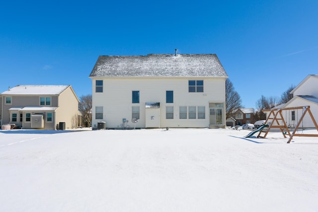 snow covered rear of property with central air condition unit and a playground