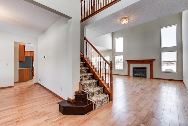 stairway featuring a tile fireplace, hardwood / wood-style flooring, a high ceiling, and a textured ceiling