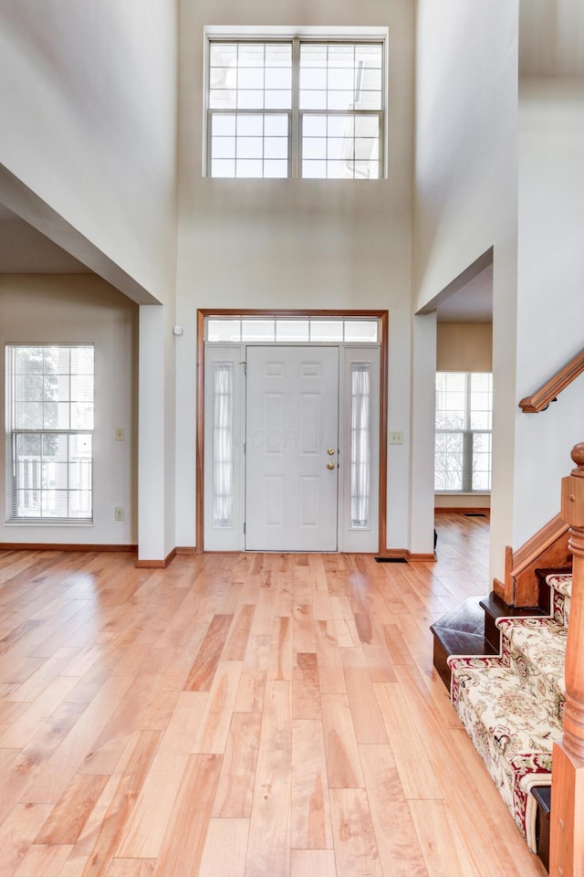 foyer entrance featuring light hardwood / wood-style flooring and a towering ceiling