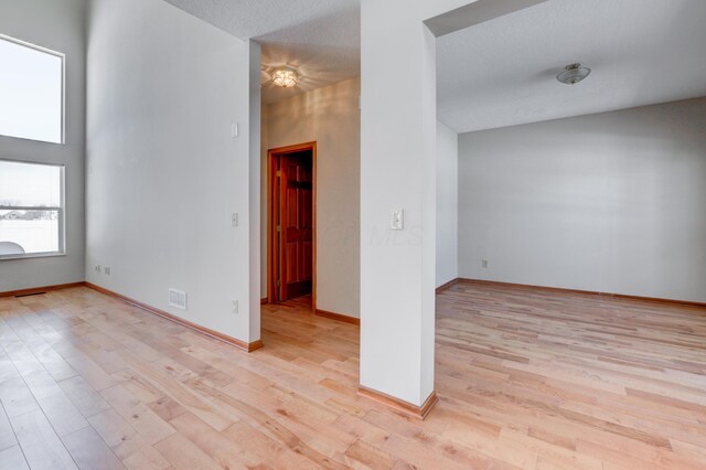 spare room with a high ceiling and light hardwood / wood-style flooring