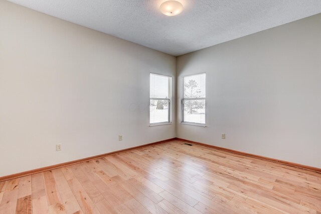 spare room with light hardwood / wood-style flooring and a textured ceiling