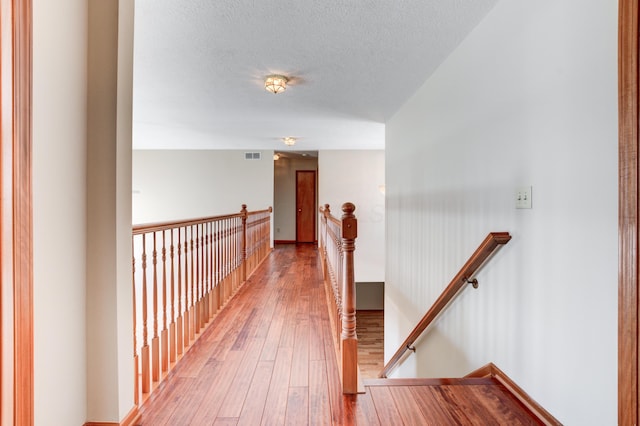 corridor with a textured ceiling and wood-type flooring