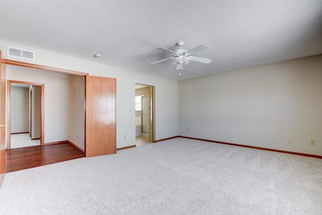 unfurnished bedroom featuring ceiling fan, carpet, a textured ceiling, and ensuite bath