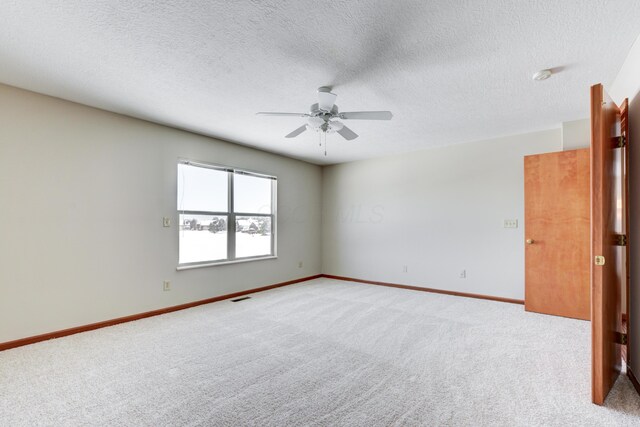 carpeted empty room featuring ceiling fan and a textured ceiling