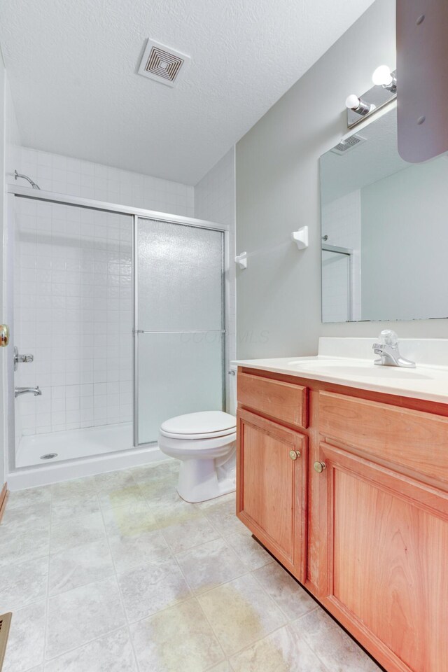 bathroom with toilet, vanity, a textured ceiling, and walk in shower