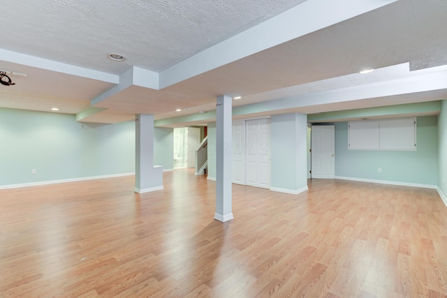 basement featuring light hardwood / wood-style floors and a textured ceiling