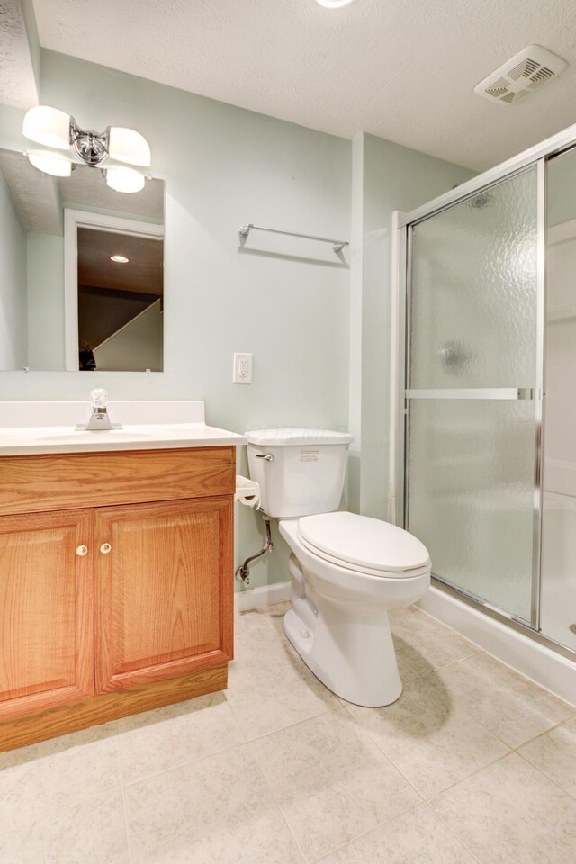 bathroom with tile patterned floors, toilet, a textured ceiling, vanity, and walk in shower