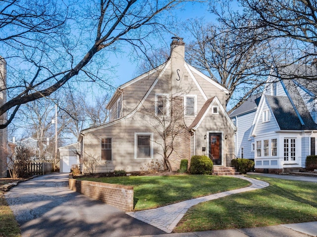 view of front facade featuring an outbuilding, a front yard, and a chimney