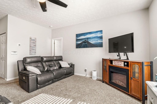 living area with ceiling fan, baseboards, a textured ceiling, and light colored carpet