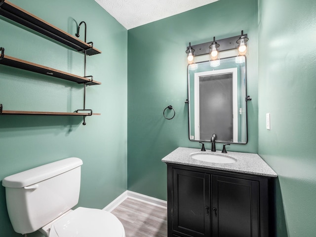 bathroom with vanity, wood-type flooring, a textured ceiling, and toilet