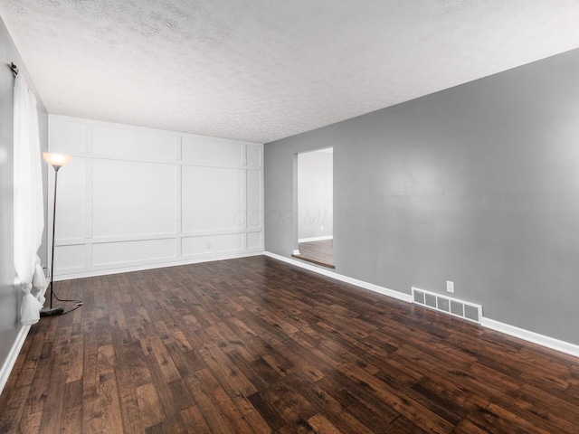 empty room featuring dark hardwood / wood-style floors and a textured ceiling