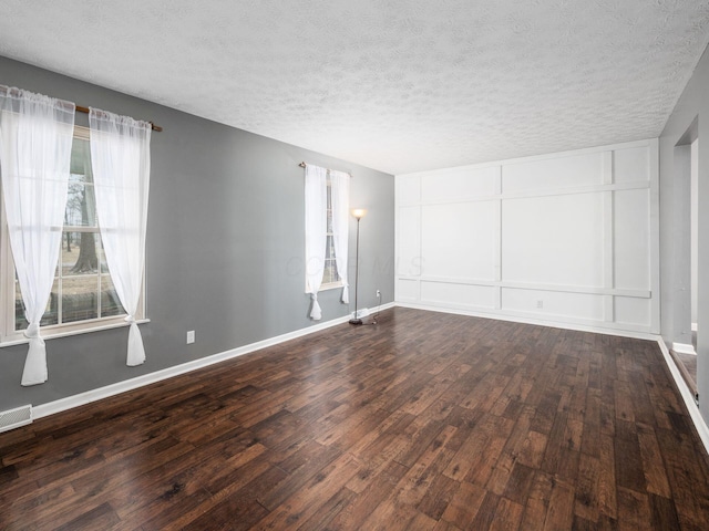 spare room featuring a textured ceiling and dark hardwood / wood-style flooring