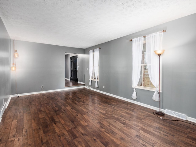 unfurnished room with dark wood-type flooring and a textured ceiling