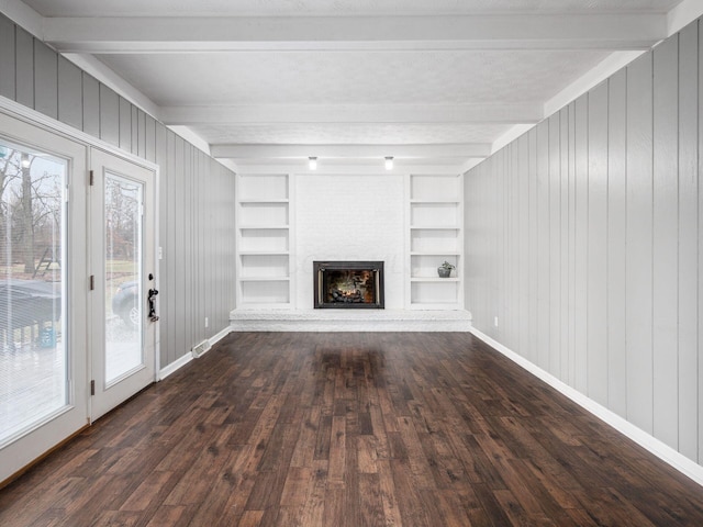 unfurnished living room featuring dark hardwood / wood-style flooring, built in shelves, a fireplace, and beamed ceiling