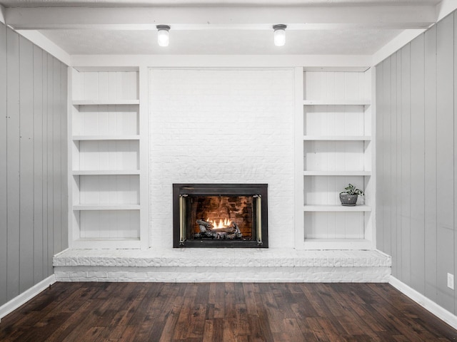 details with built in shelves, wood walls, wood-type flooring, beamed ceiling, and a fireplace