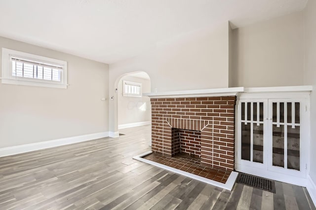 1437 Manchester Ave, Columbus, OH 43211 - unfurnished living room with a fireplace, arched walkways, wood finished floors, and baseboards