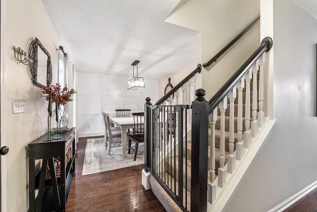 stairs with hardwood / wood-style floors, a notable chandelier, and a textured ceiling