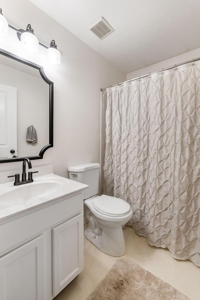 bathroom with toilet, vanity, a textured ceiling, and tile patterned floors