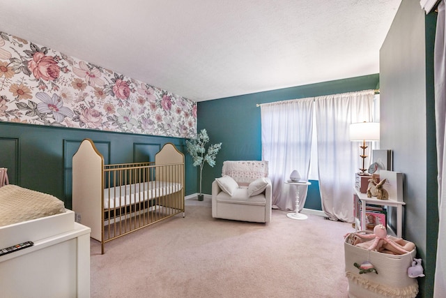 bedroom featuring a crib, carpet flooring, and a textured ceiling