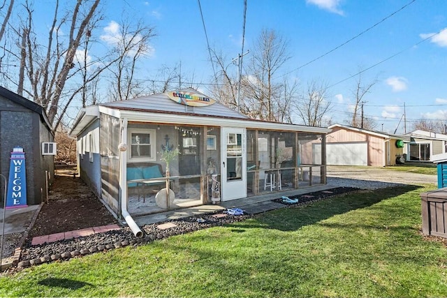 view of front facade with a garage, driveway, a sunroom, an outbuilding, and a front lawn