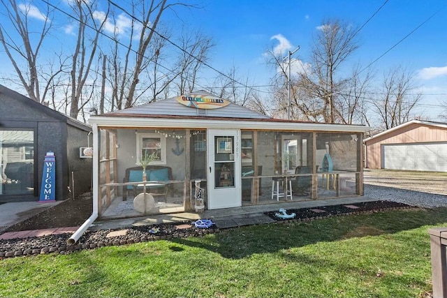 view of front of house with a sunroom, stucco siding, a front lawn, and an outbuilding