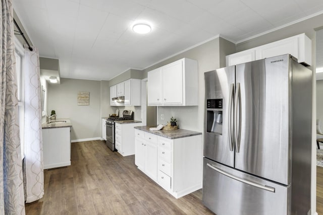 kitchen with sink, white cabinets, dark stone counters, hardwood / wood-style flooring, and stainless steel appliances