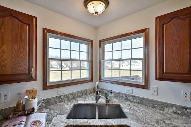 kitchen with sink, light stone countertops, and a textured ceiling