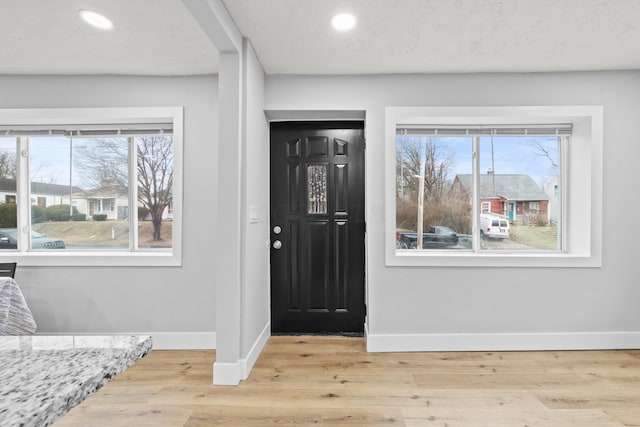 entryway featuring a healthy amount of sunlight, light hardwood / wood-style floors, and a textured ceiling