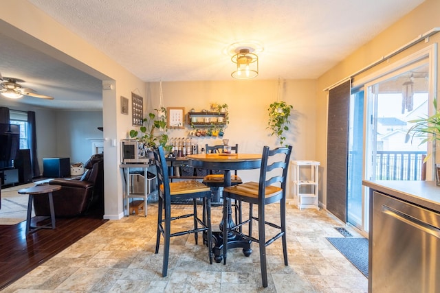 dining space featuring ceiling fan, a healthy amount of sunlight, and a textured ceiling